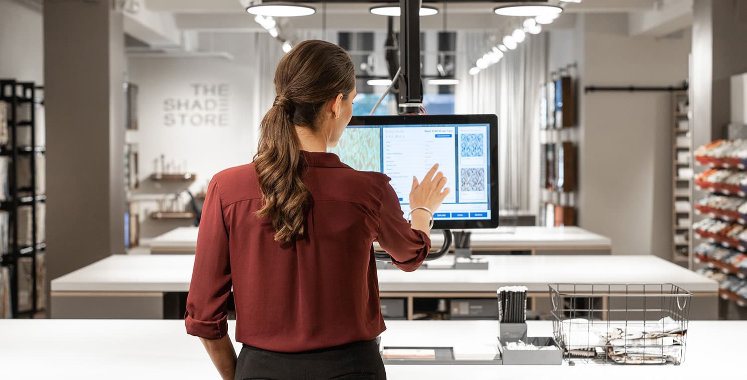 A retail associate uses an interactive Elo touchscreen to browse product options in a showroom environment, demonstrating how touch displays enhance guided selling and customer consultations.